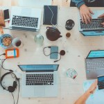 Executive recruitment in tech- Group of diverse executive professionals discussing strategies, surrounded by tech devices in a modern office setting