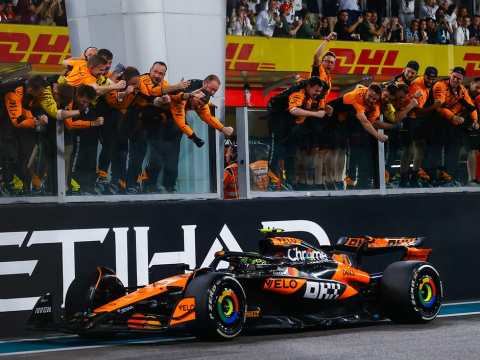 McLaren MCL38 Formula 1 car in iconic papaya orange livery racing on track during 2024 championship-winning season, illustrating the complete team approach to sustained manufacturing excellence