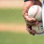 Close-up of a baseball player holding two baseballs on a field, symbolizing strategy and execution in sales leadership.
