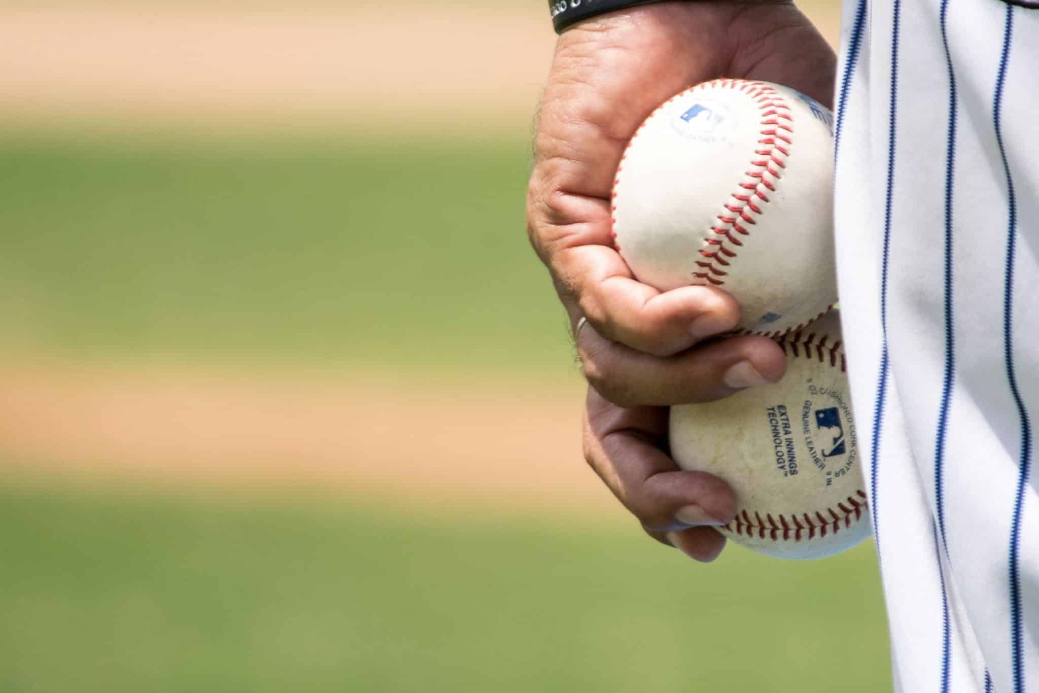 Close-up of a baseball player holding two baseballs on a field, symbolizing strategy and execution in sales leadership.