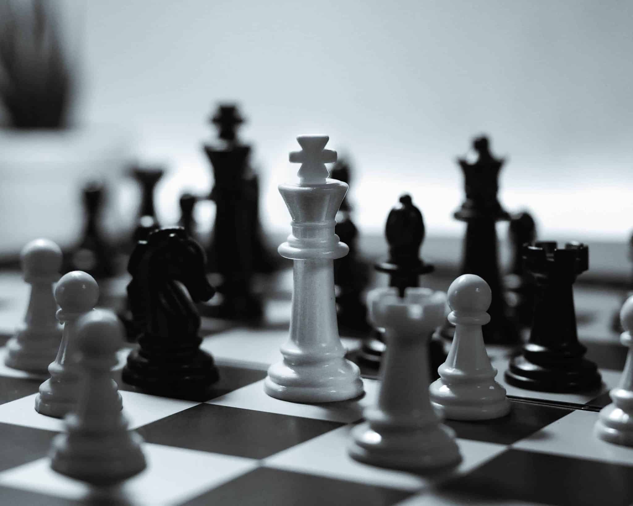 A close-up of a modern chessboard showing a few key pieces in a strategic formation, representing the thoughtful process of building a board of directors.