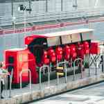 F1 team principal collaborating with pit wall crew contrasted with founder facing empty COO chair representing leadership diagnostic