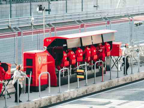 F1 team principal collaborating with pit wall crew contrasted with founder facing empty COO chair representing leadership diagnostic