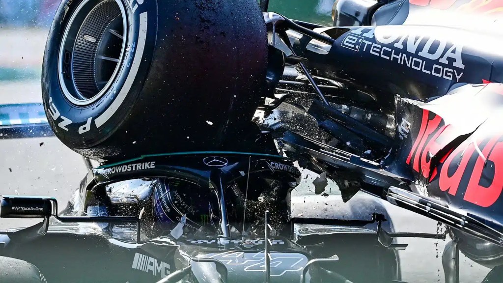 Max Verstappen's Red Bull car lands on top of Lewis Hamilton's Mercedes at Monza 2021, with the Halo device visibly protecting Hamilton's head from the rear wheel