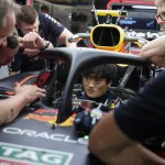 Race driver stationary in pit lane while competitors pass on track, representing the cost of accepting a counter-offer while career momentum moves on