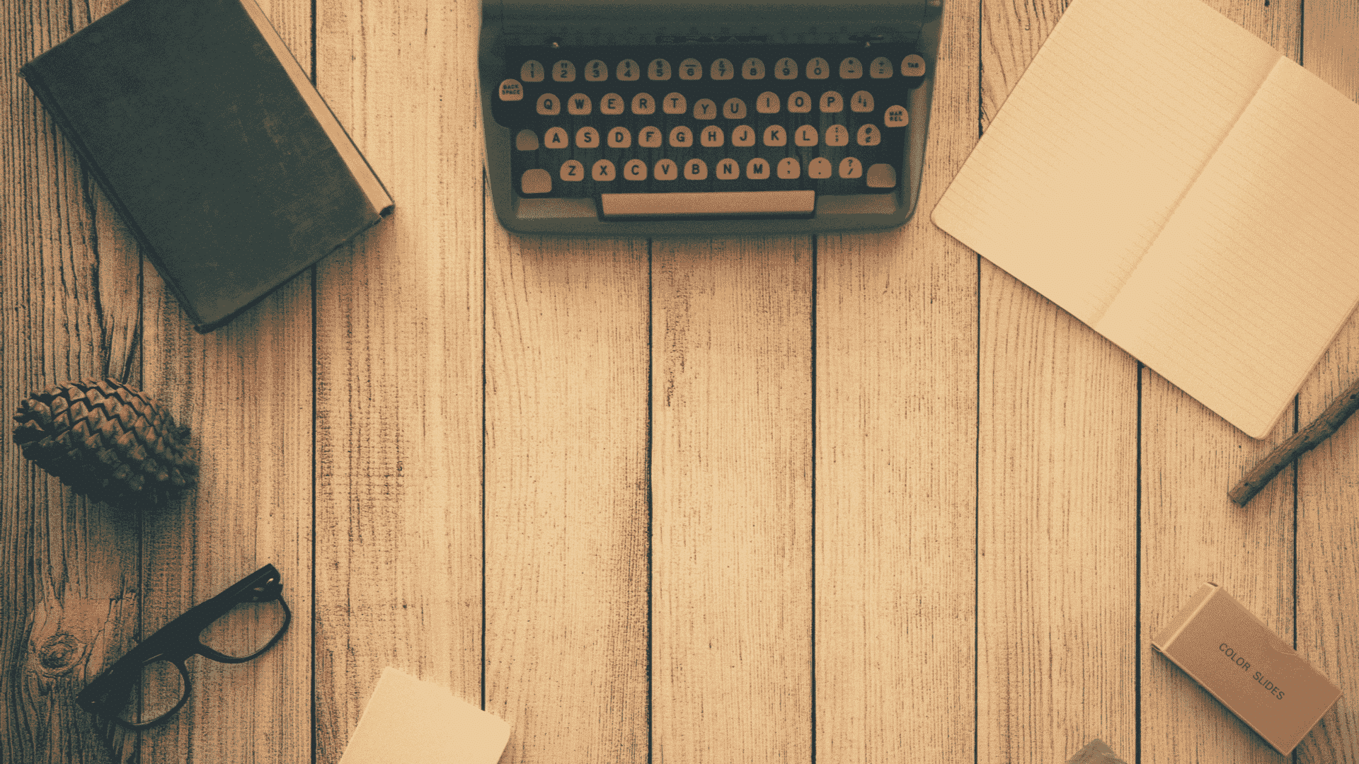 Vintage typewriter and stacked books on a wooden desk, representing Charlie Solorzano's articles on leadership