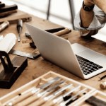 Family Business Succession: A handwritten ledger and a laptop side by side on a worn wooden desk, representing two generations of running a business