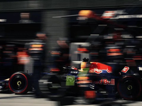 Formula 1 garage with a car mid-rebuild on stands, symbolizing executive hiring readiness before results