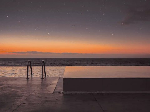 Infinity pool edge meeting the horizon at dawn, representing the resort general manager's role between brand and asset