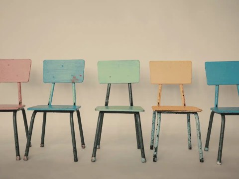 Five identical chairs arranged symmetrically around a table, representing search committee bias toward sameness