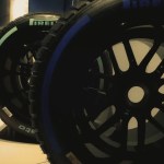 Worn Formula 1 tire resting against a pit wall, symbolizing sports executive calibration between pace and durability