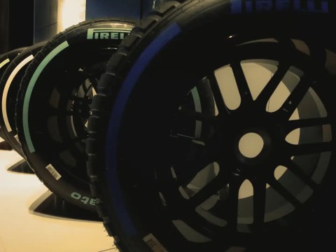 Worn Formula 1 tire resting against a pit wall, symbolizing sports executive calibration between pace and durability