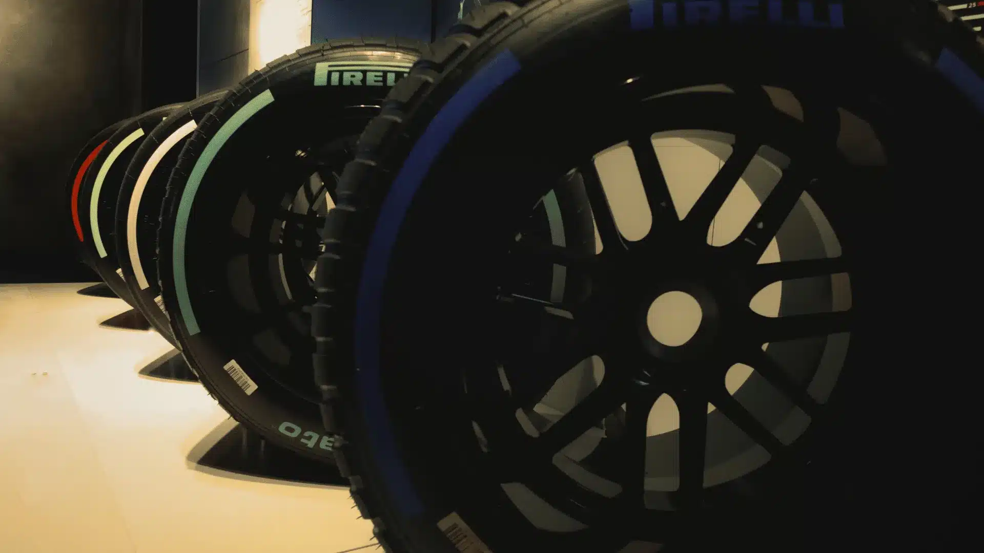 Worn Formula 1 tire resting against a pit wall, symbolizing sports executive calibration between pace and durability